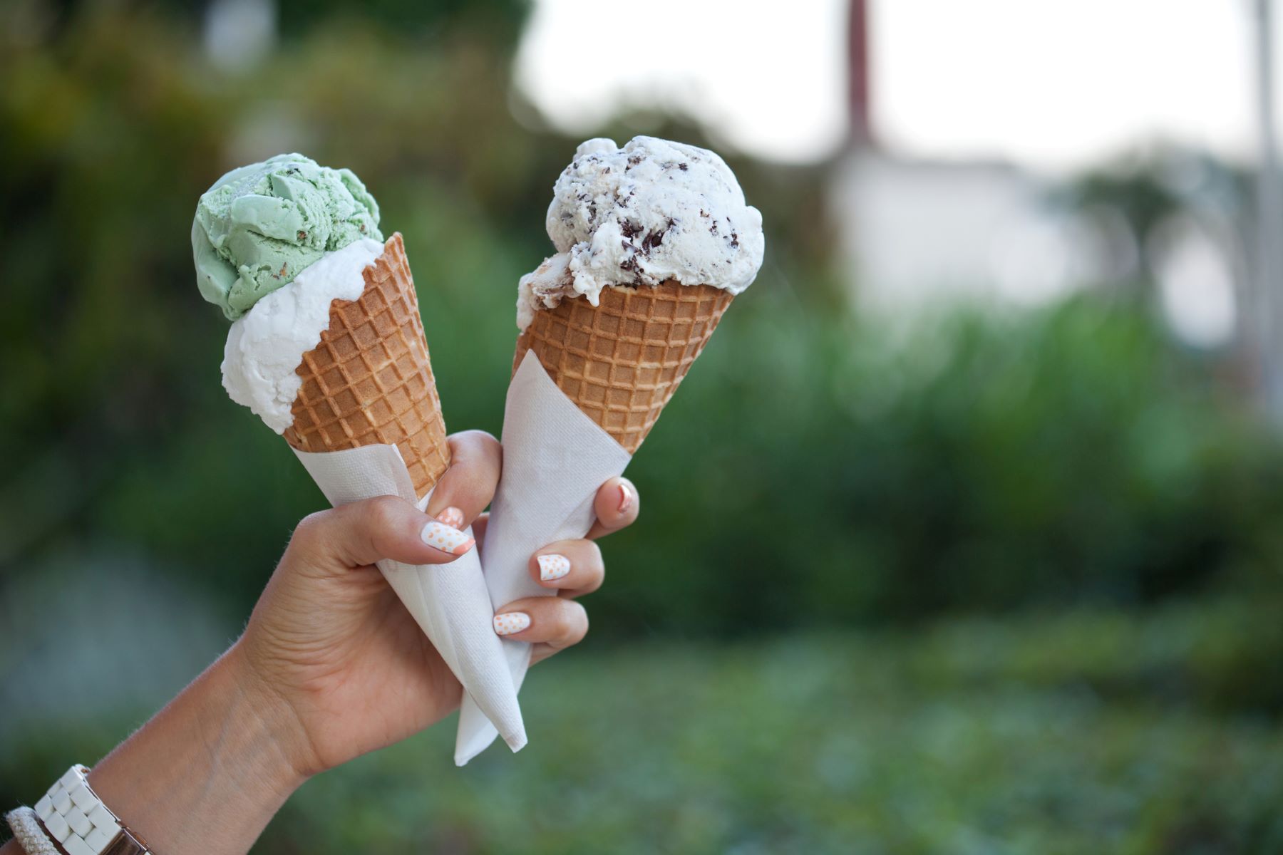 Person holding two ice cream cones.