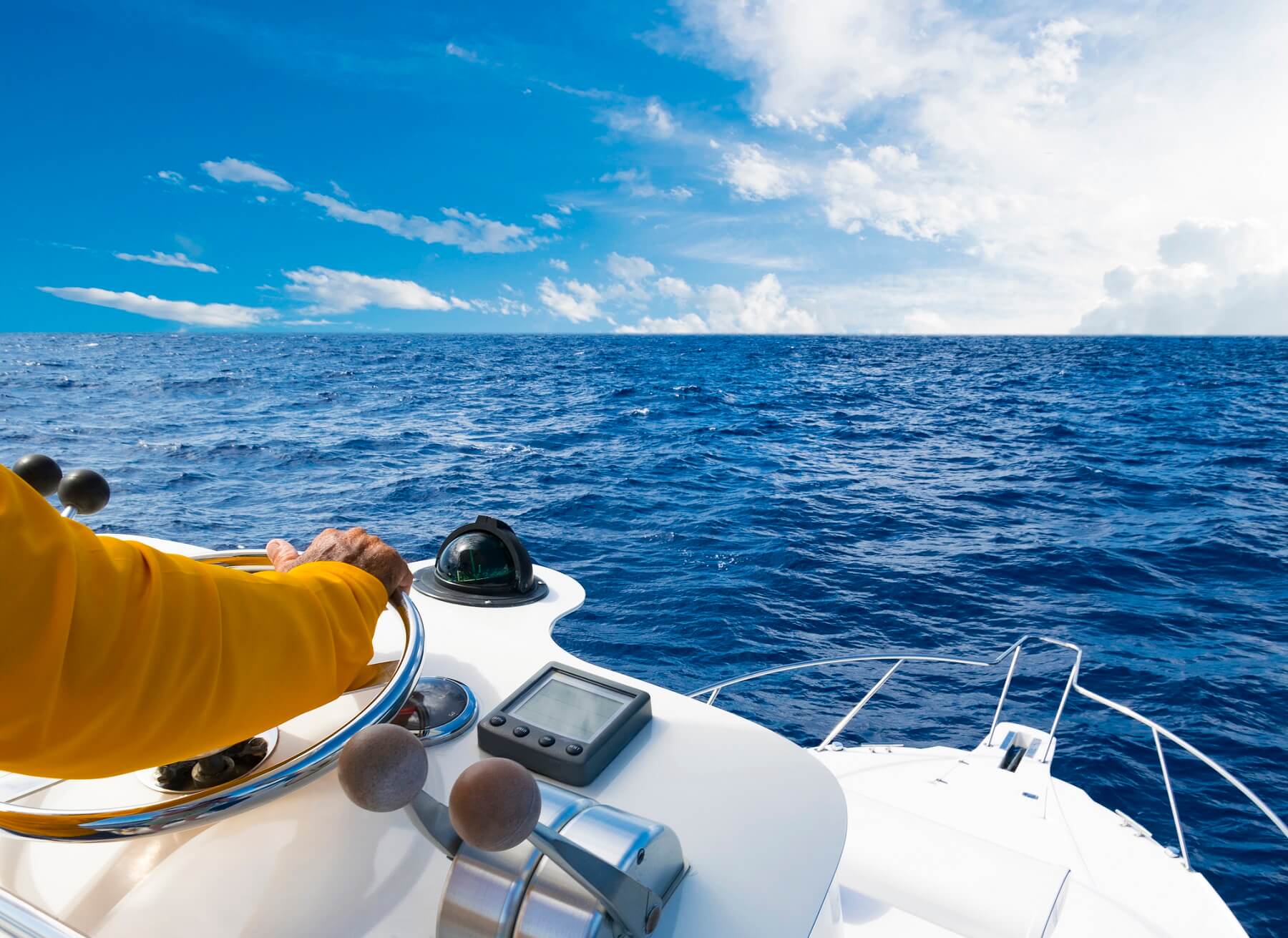 Hand of captain on steering wheel of a motor boat in the blue ocean fishing trip