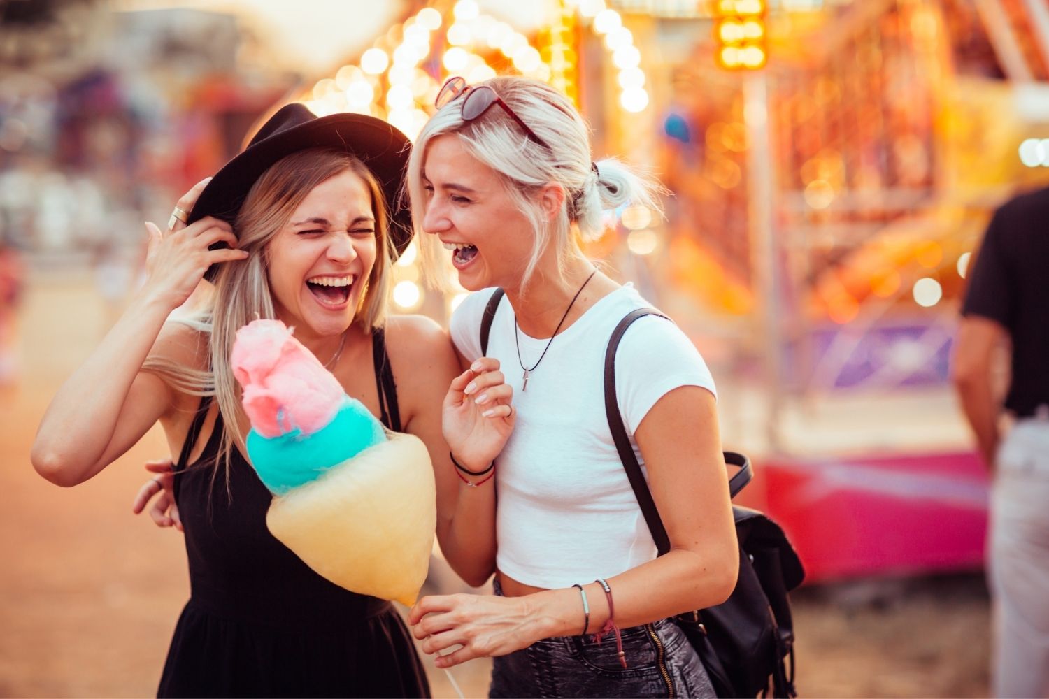 Two girls having cotton candy at an amusement park.